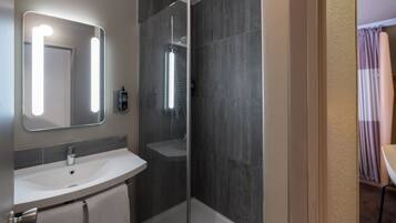 Une salle de bain moderne avec un meuble-lavabo, un miroir et une cabine de douche.