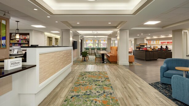 Eine geräumige Hotelhalle mit einer Rezeption, einer Sitzecke und einer kleinen Küche im Hintergrund.