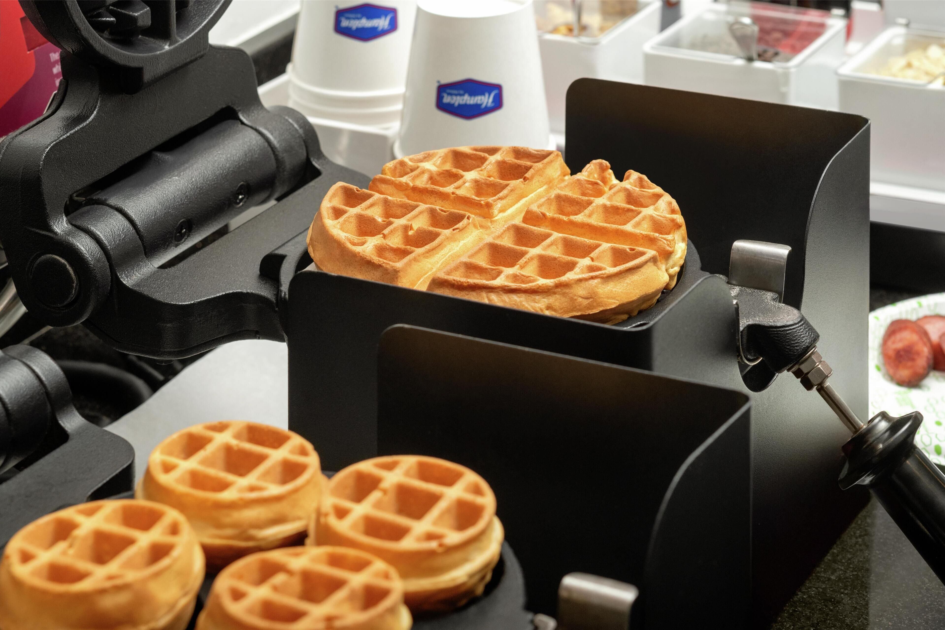 A waffle iron with waffles in various stages of cooking.