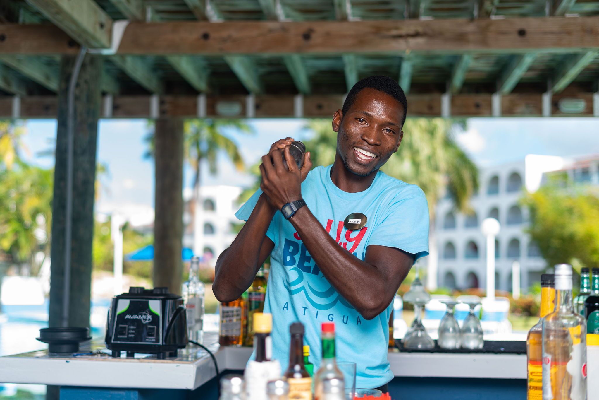 A person at a bar with a counter, various bottles, and a radio.