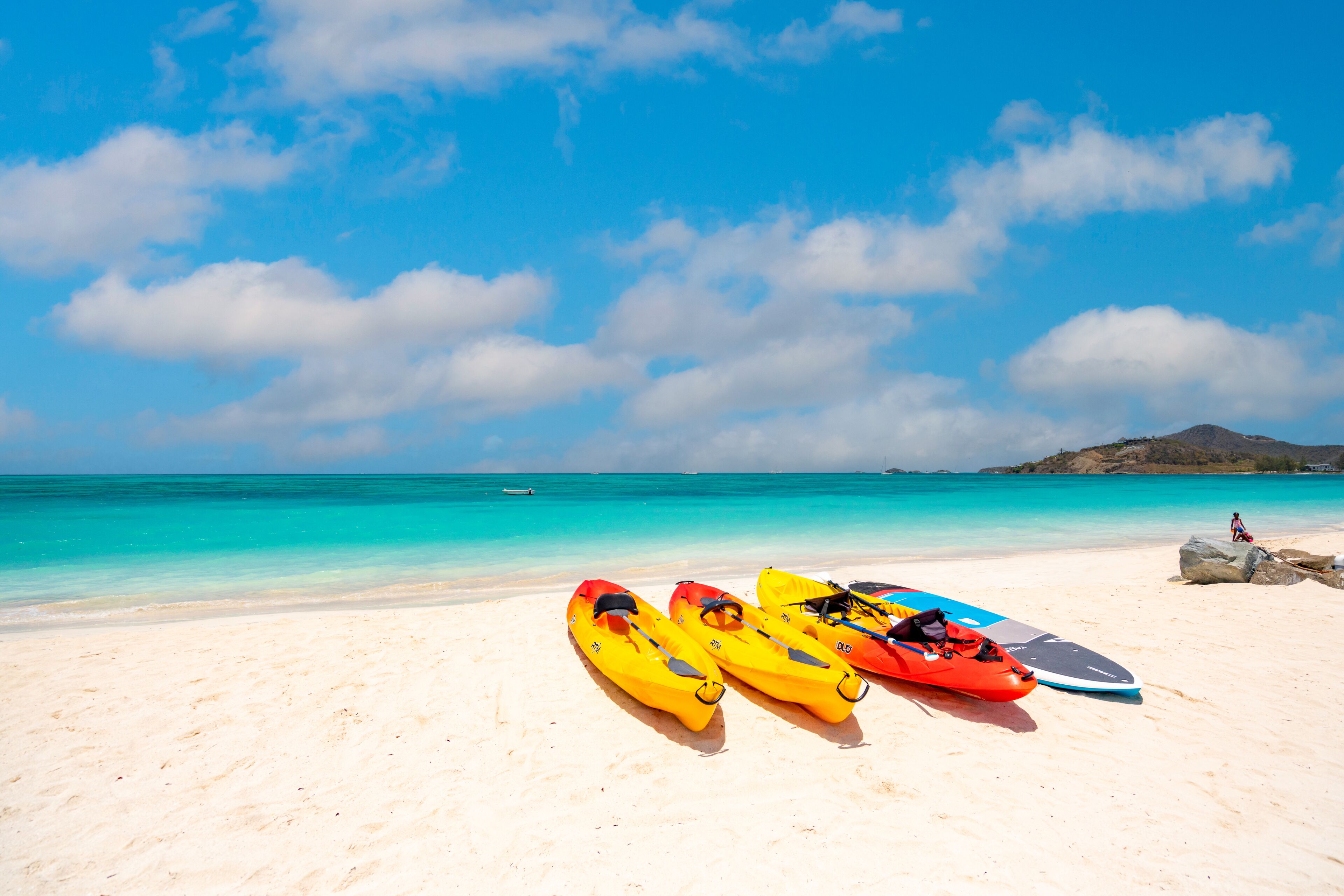 Una playa con kayaks y una tabla de surf.