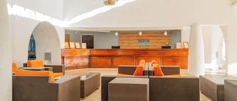 A lobby with wicker furniture, a reception desk, and a chandelier.