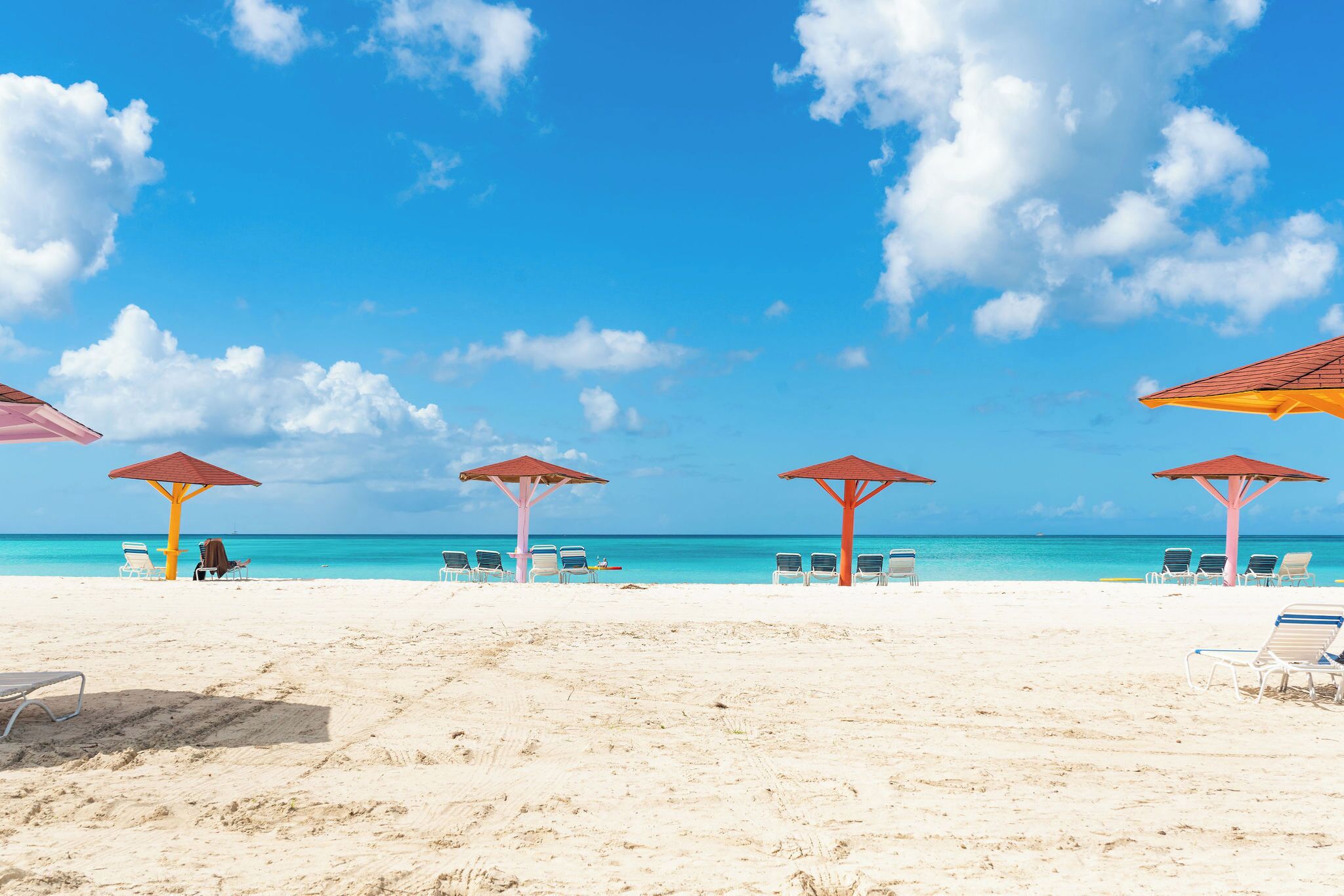 Een strand met parasols en ligbedden.