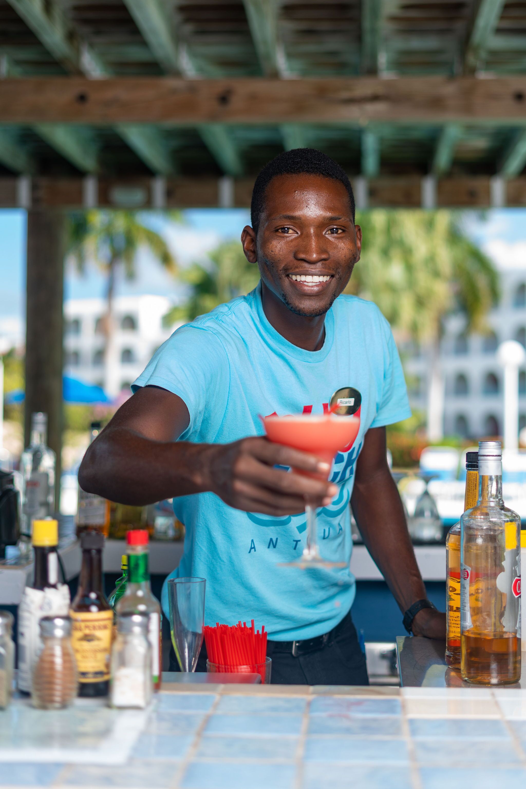 A person preparing a drink at a bar with various bottles and glasses.