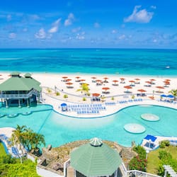 Relax by the resort's large oval-shaped pool surrounded by sun loungers and umbrellas, with access to a sandy beach and ocean views.