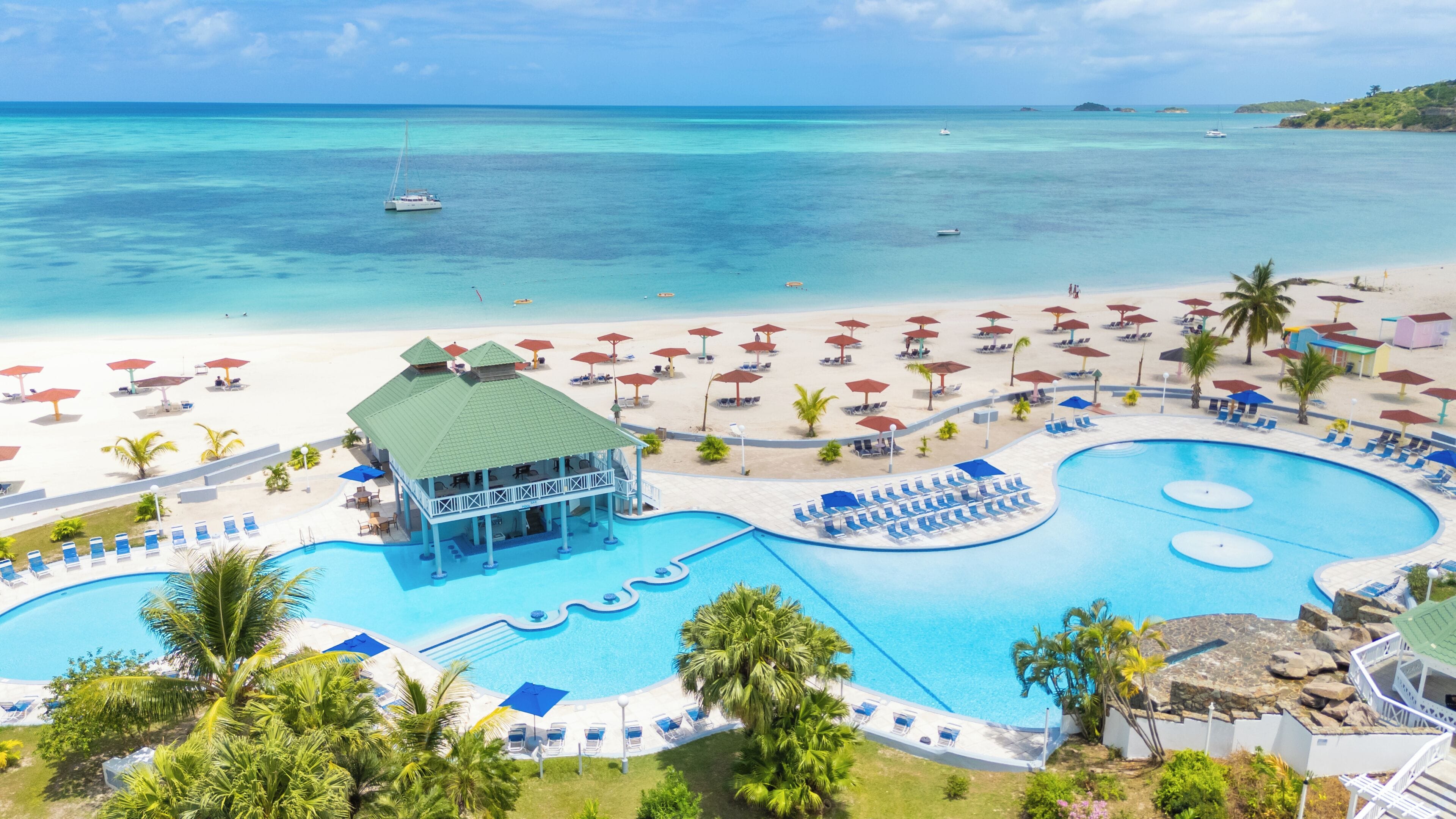 Um resort com uma piscina grande, área de praia e vista para o oceano.
