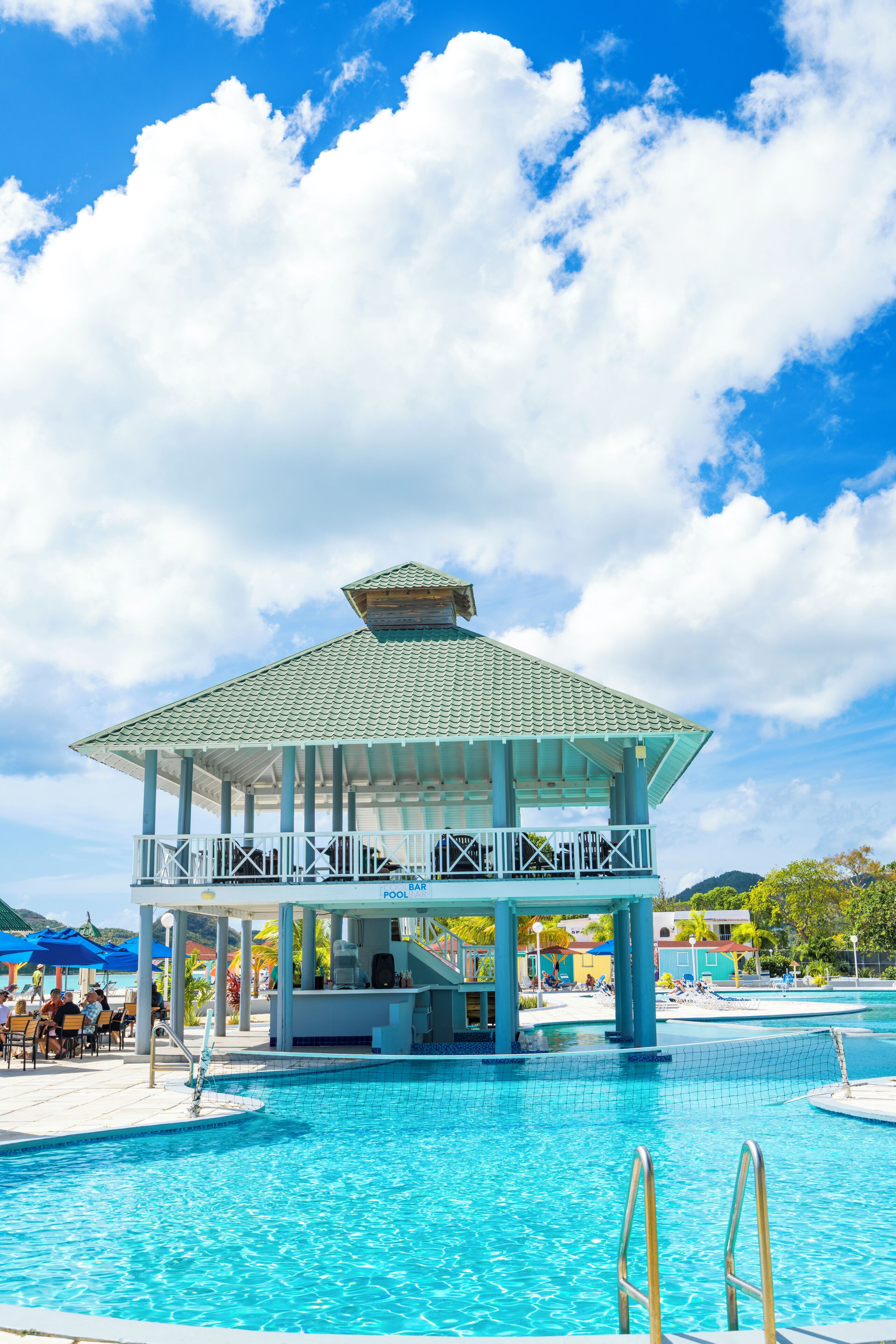 A pool area with a covered pavilion, lounge chairs, and a bar.