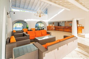 A spacious lobby with wicker furniture, a reception desk, and arched doorways. - Jolly Beach Antigua - All-inclusive (Jolly Harbour)