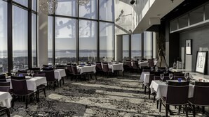 A restaurant with tables set for dining, large windows, and a view of the city. - Grand Traverse Resort And Spa (Williamsburg)