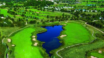 Golfers can enjoy a serene setting with a central water feature, lush greenery, and sand bunkers.