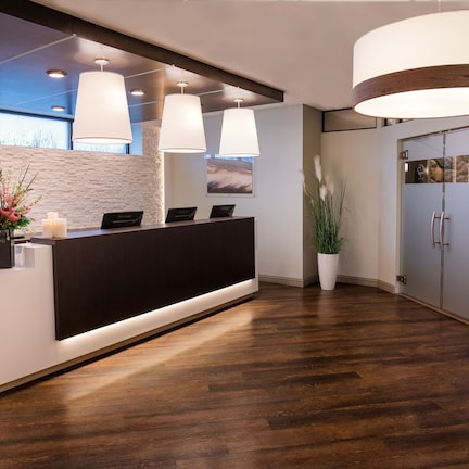 A reception area with a modern design, featuring a reception desk, a potted plant, and a display of products on shelves.