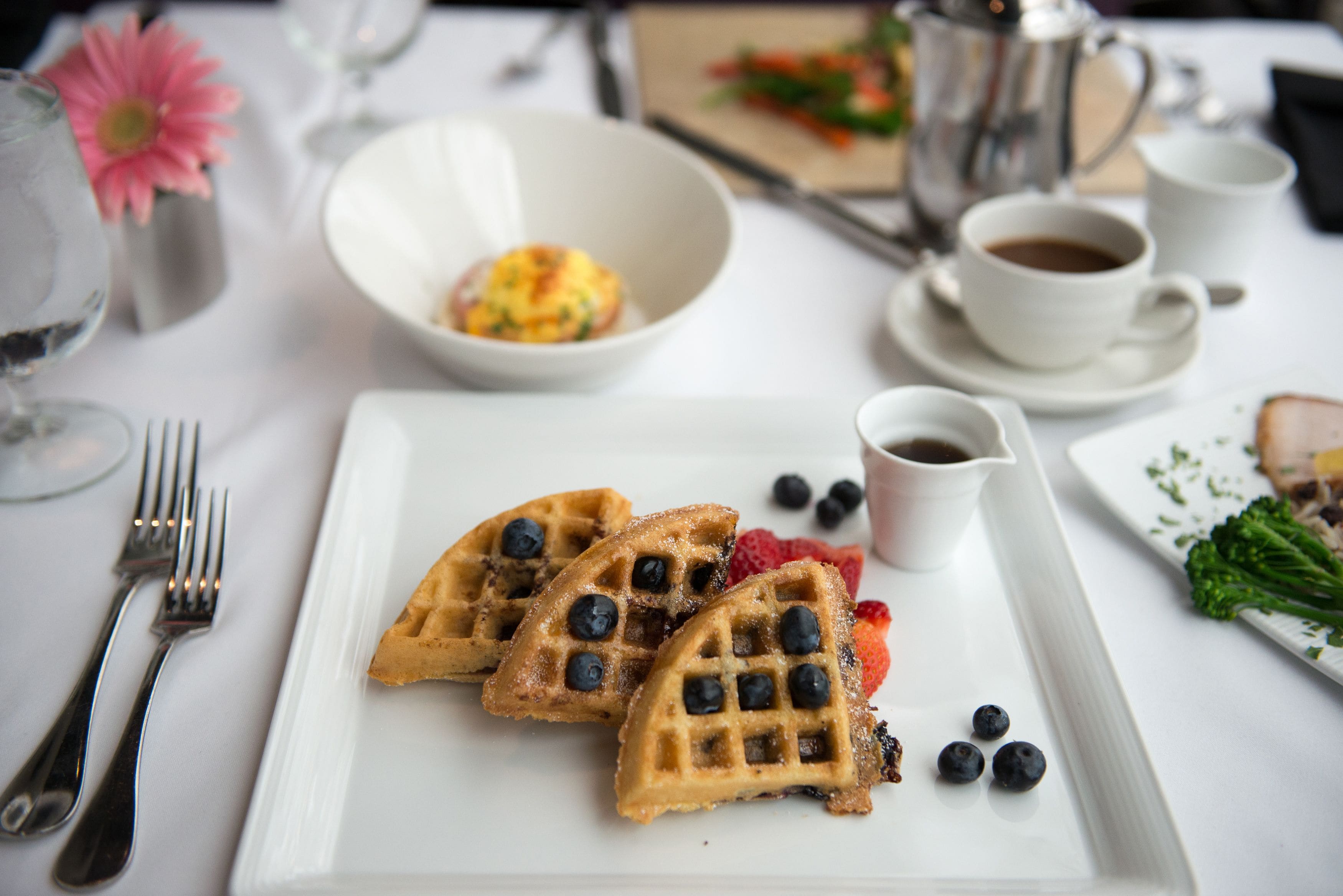 A breakfast setting with waffles, blueberries, and coffee.