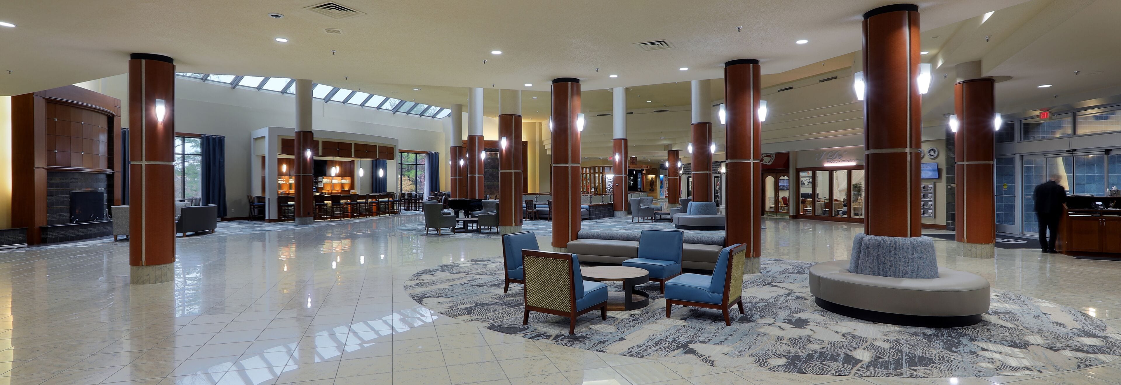 A spacious lobby with high ceilings, large pillars, and a mix of seating areas including sofas and chairs.