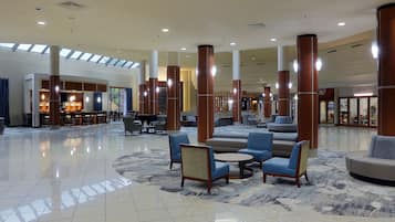 A spacious lobby with high ceilings, large pillars, and a mix of seating areas including sofas and chairs.