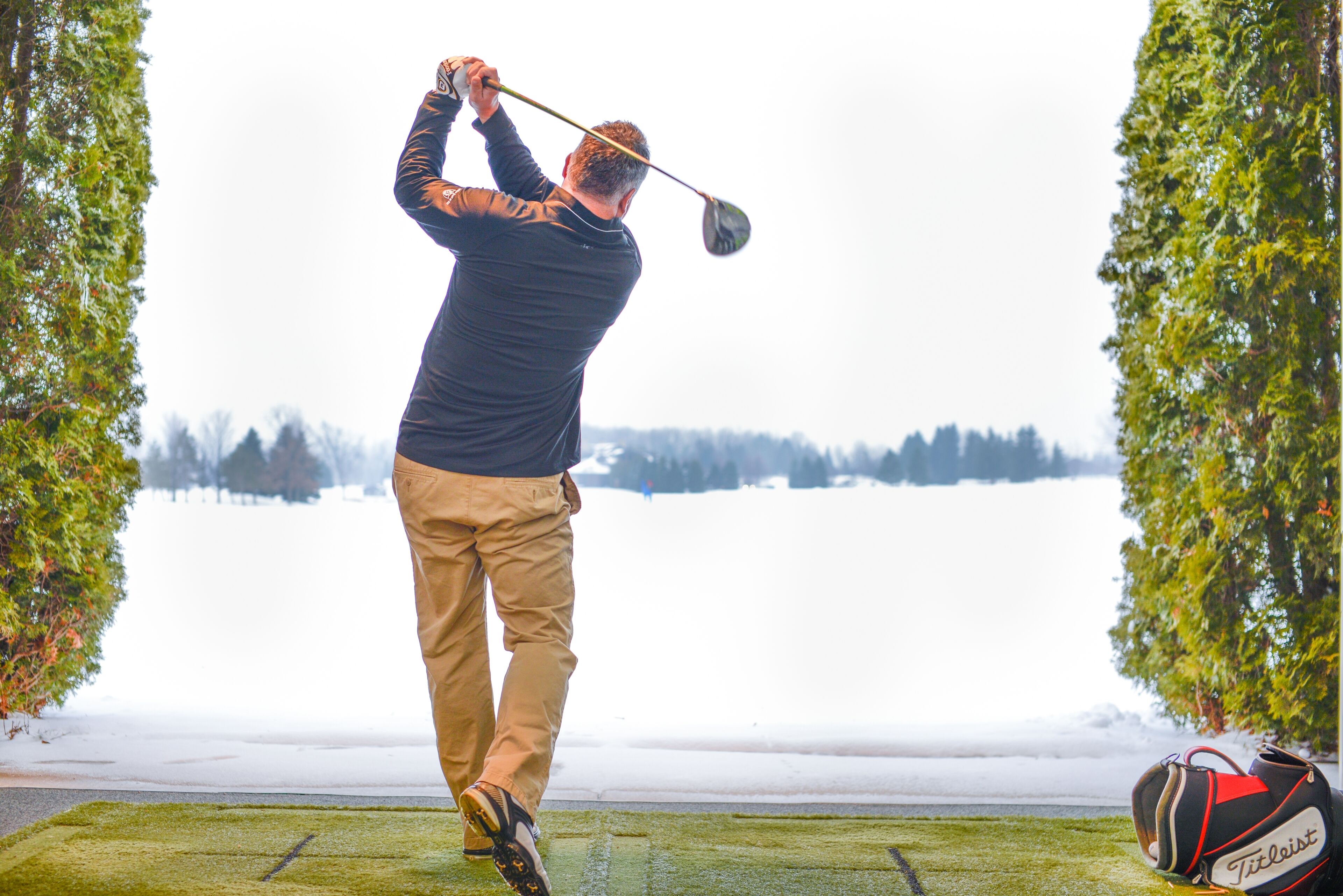 A person playing golf on a course with a bag of golf balls and a golf club.