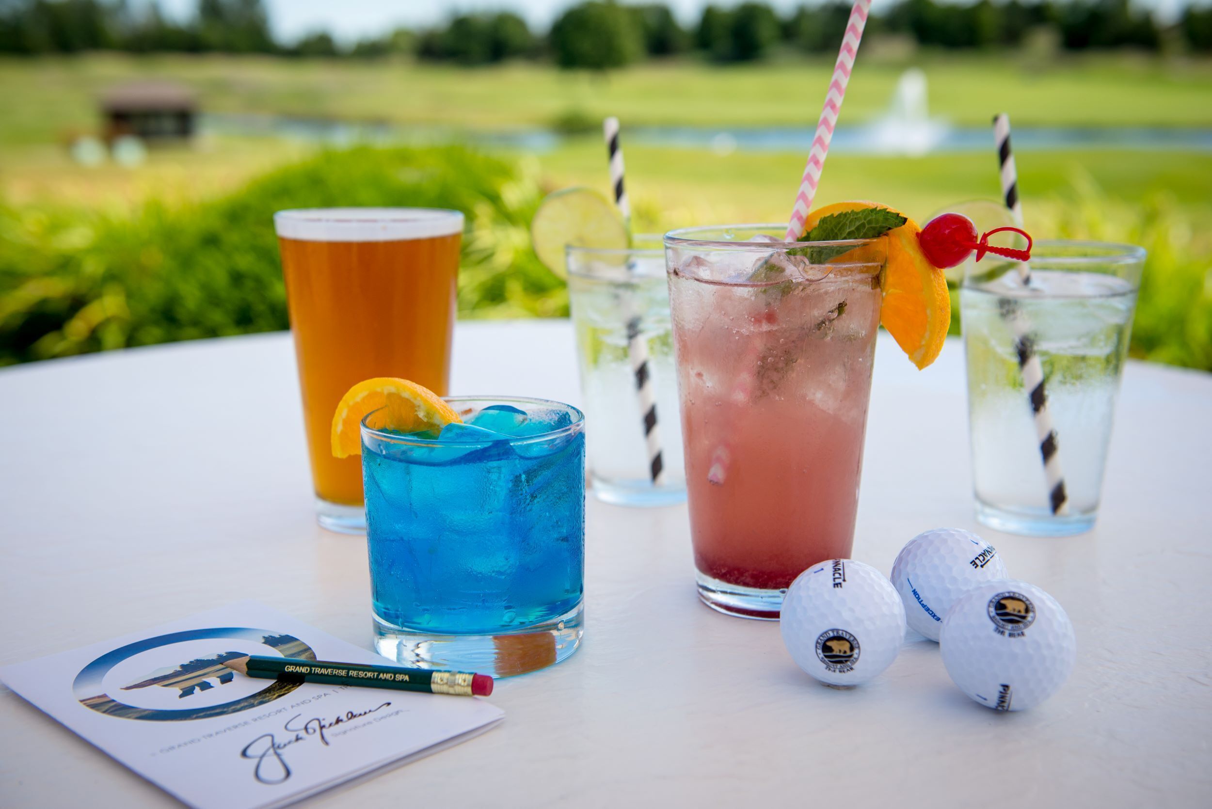 Ein Tisch mit vier Getränken, Golfbällen und einer Visitenkarte.