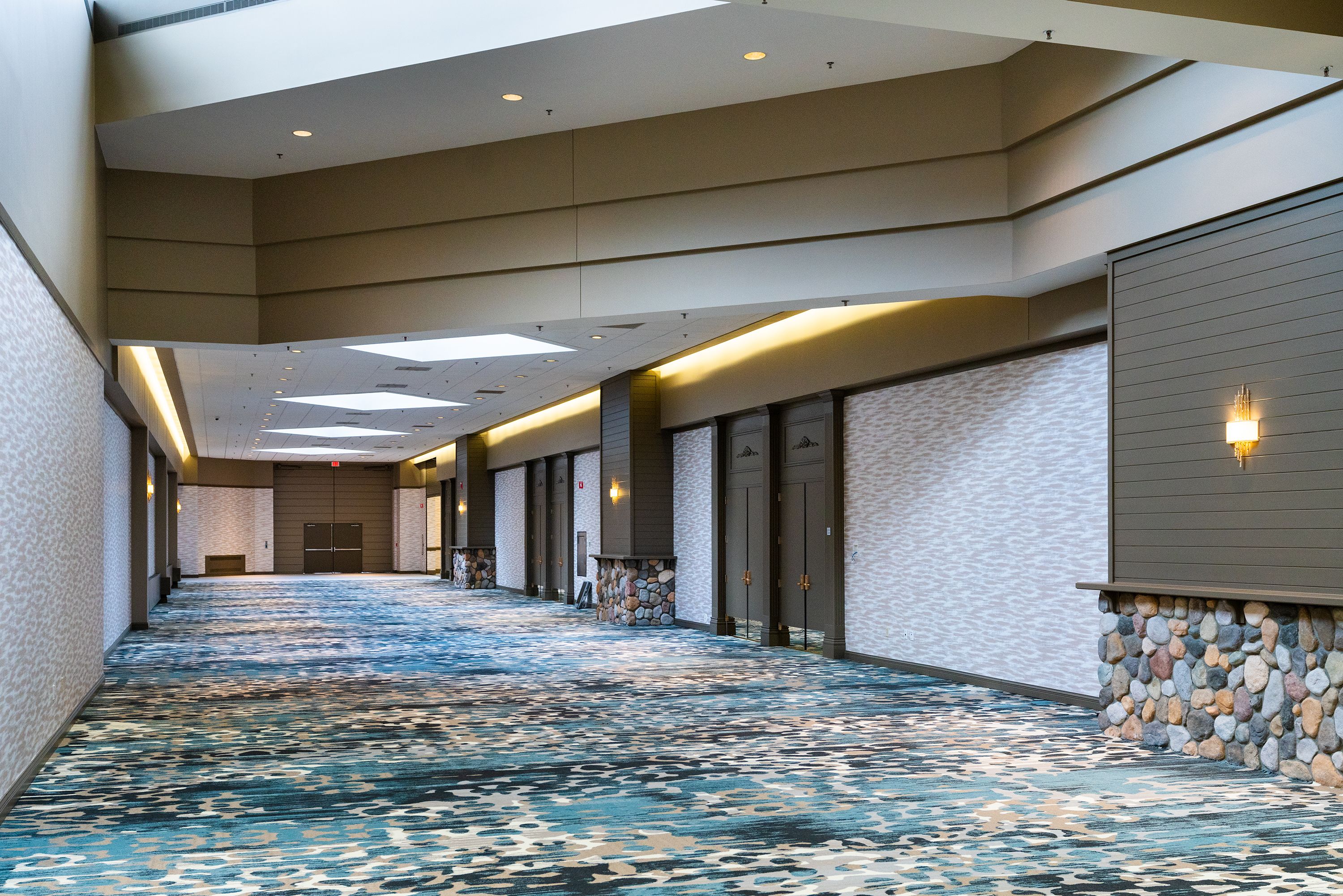 A long, narrow hallway with a patterned carpet and stone accents on the walls.