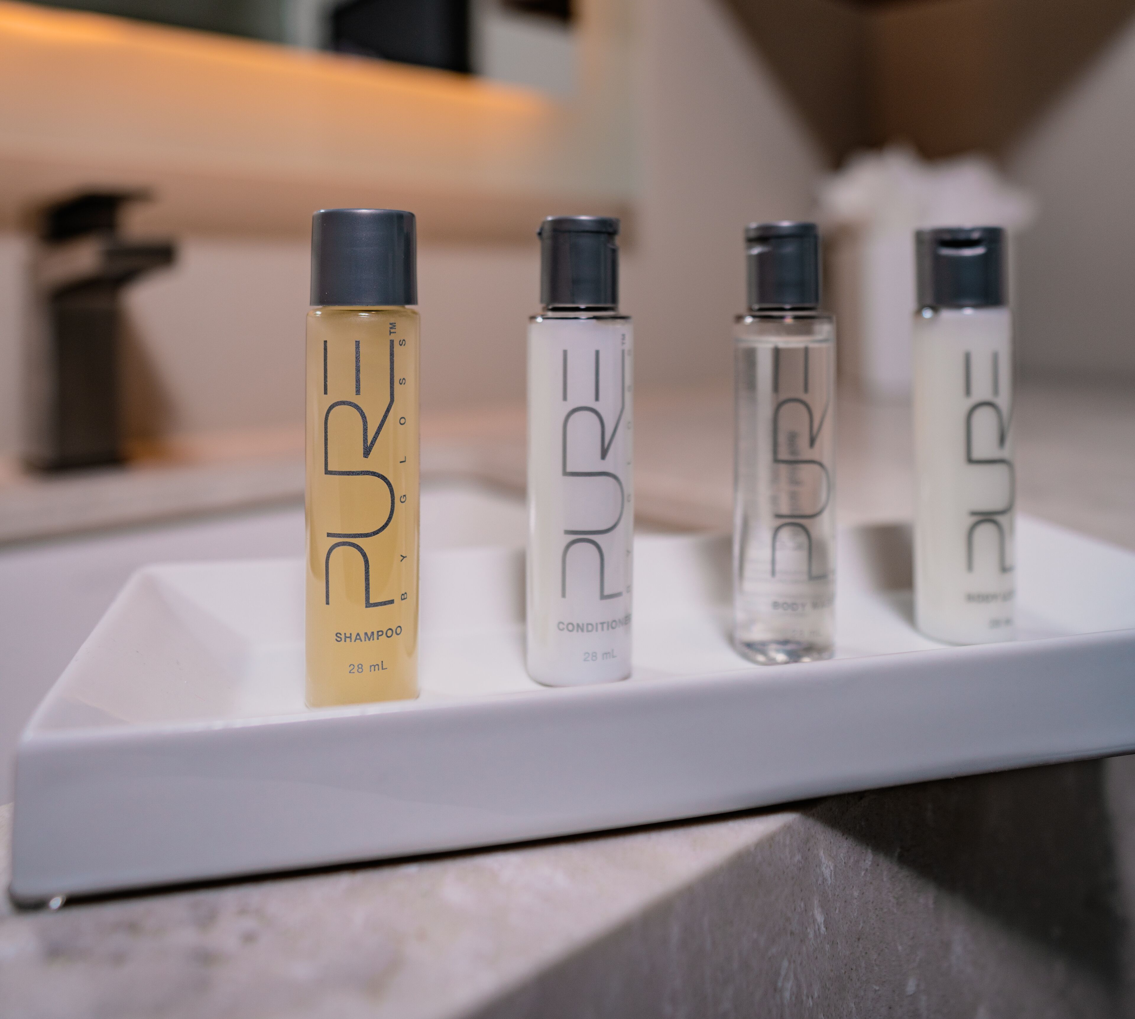 A white shelf with four bottles of PURE shampoo and conditioner.