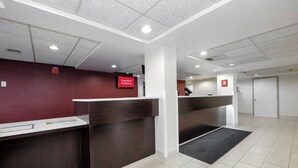 A reception area with a counter, a red sign indicating free Wi-Fi, and a door in the background. - Red Roof Inn Gadsden (Gadsden)