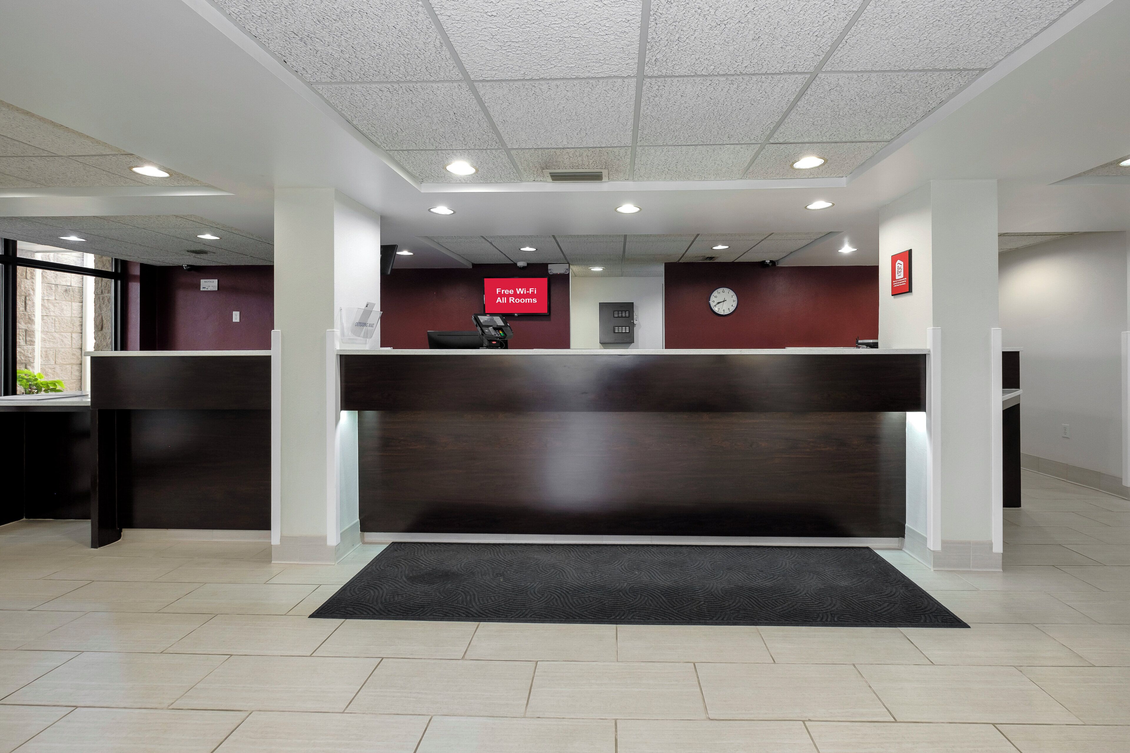 A reception desk with a digital clock, a notice board, and a sign indicating free Wi-Fi availability.