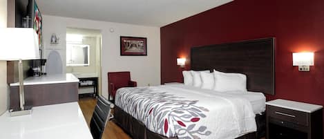 Une chambre d’hôtel comprenant un lit, des tables de chevet, un bureau, une chaise, un miroir et un tableau accroché au mur.