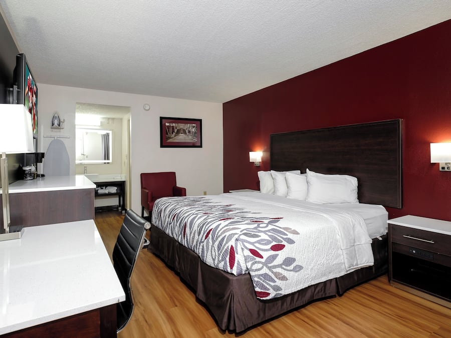 Een hotelkamer met een bed, nachtkastjes, een bureau, een stoel, een spiegel en een aan de muur hangend schilderij.