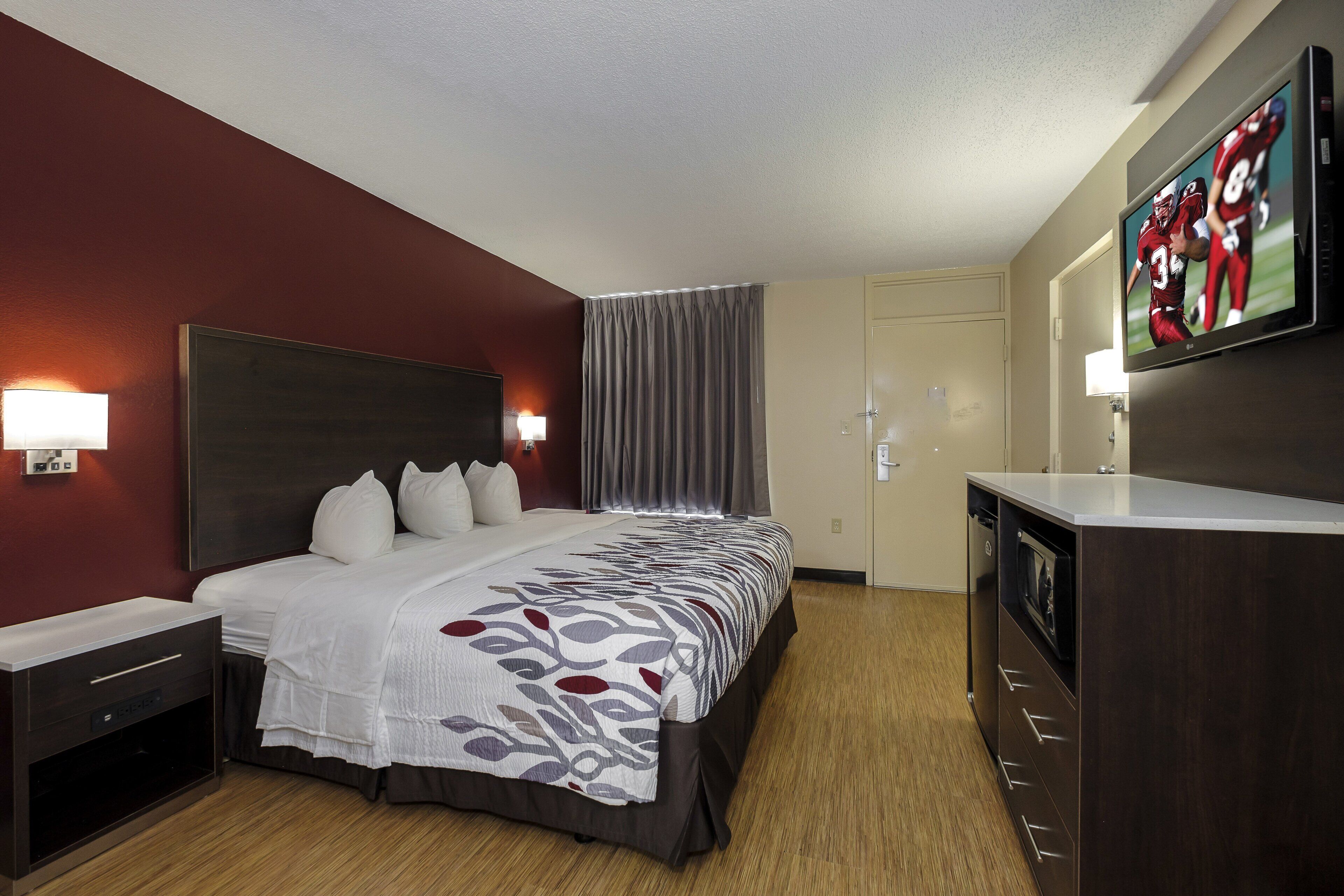 A hotel room with a large bed, a TV, a desk, and a wardrobe.