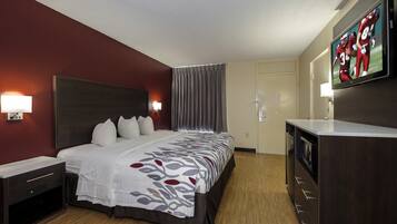 A hotel room with a large bed, a TV, a desk, and a wardrobe.