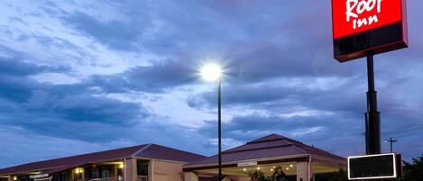 Un hotel Red Roof Inn con cielo despejado, entrada bien iluminada y un cartel que indica 3.6 metros de altura.