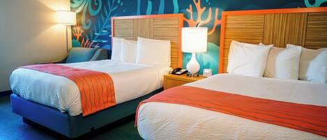 Two double beds with wooden headboards, a nightstand with a lamp, and a wall mural with marine life.