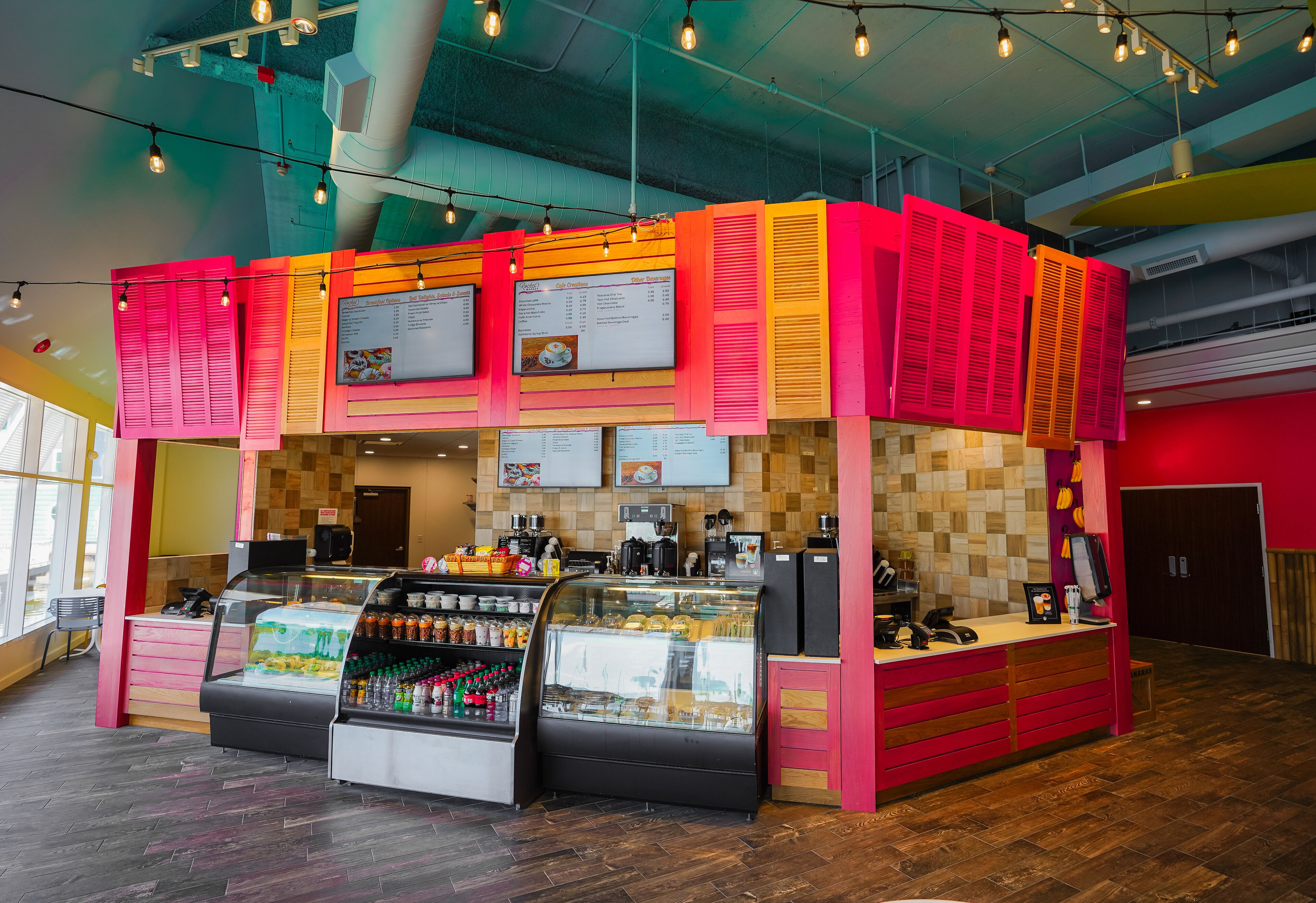 A brightly lit food court with a counter, display cases, and menu boards.