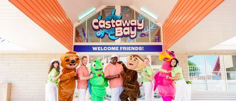 A group of people in various costumes standing in front of a sign that reads "Castaway Bay."