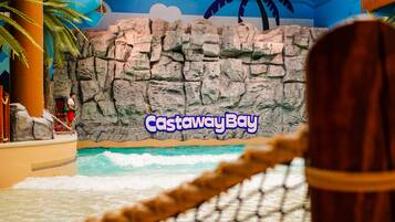 A water play area with a rock wall backdrop and a rope barrier.