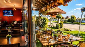 Un restaurant doté d’une salle à manger intérieure et d’une terrasse offrant une vue sur la rue.