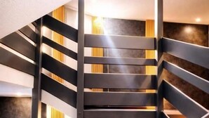 Un escalier moderne avec des rampes noires et des éléments décoratifs en bois, menant à un niveau inférieur.