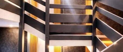 A modern staircase with black railings and wooden accents, leading to a lower level.