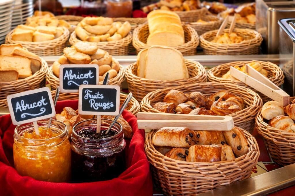 A variety of breads and pastries displayed in wicker baskets with labels for 'Apricot' and 'Fruits Rousses'.