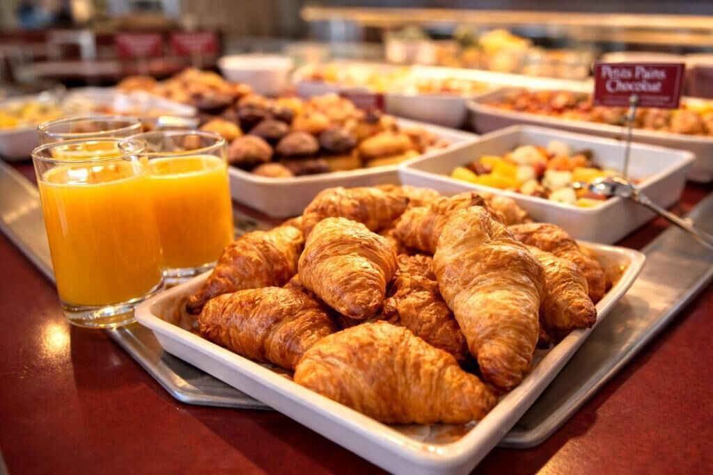 En morgenmadsbuffet med croissanter, appelsinjuice og et udvalg af andre bagværk.