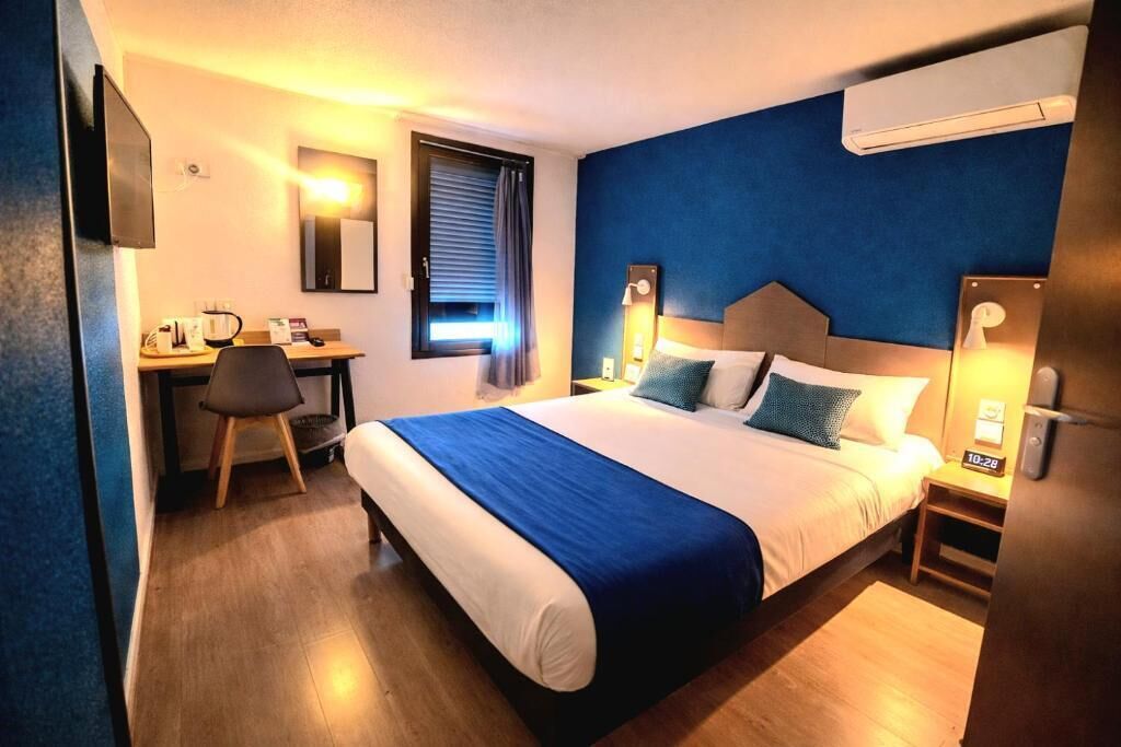 Habitación de hotel con cama, escritorio, silla y televisión.