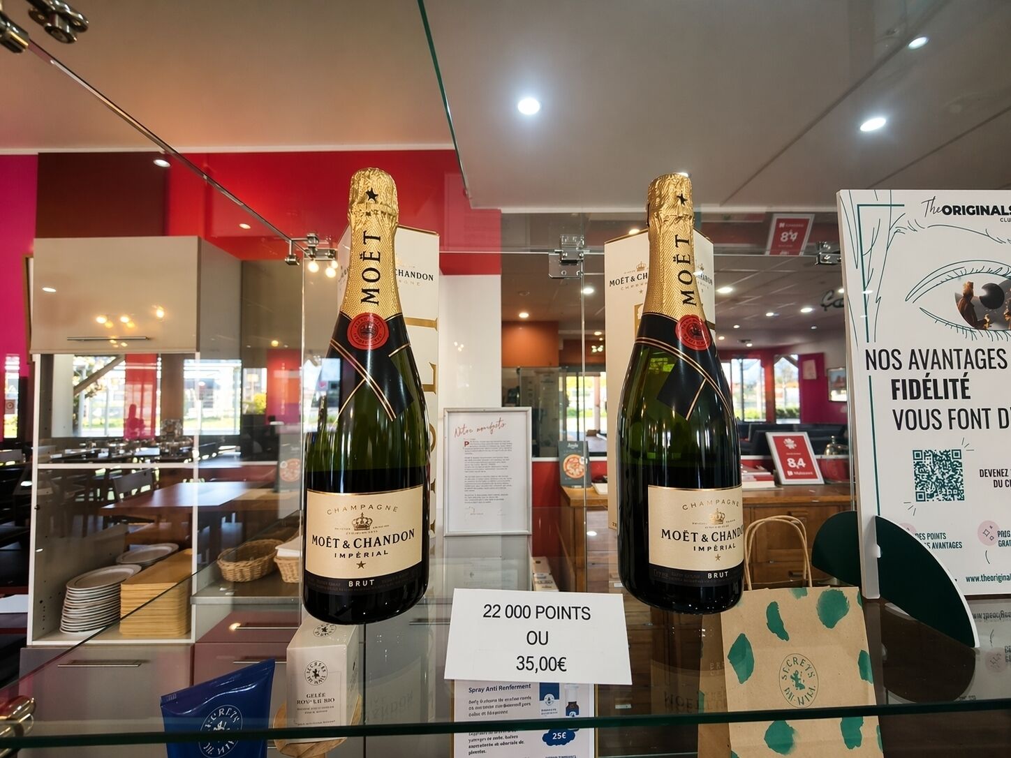 Two bottles of Moët & Chandon champagne on display with a sign indicating a points system for purchasing.