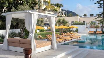 Una piscina al aire libre, sombrillas, sillones reclinables de piscina