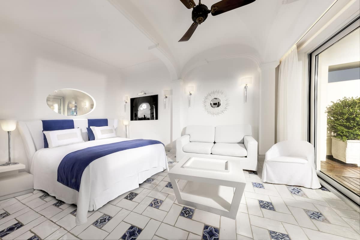A modern hotel room with a bed, white sofa, and a coffee table.