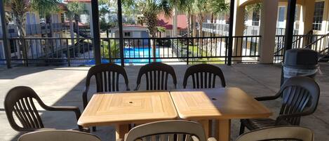 Un espace extérieur abrité, aménagé avec une table et des chaises, et offrant une vue sur la piscine.