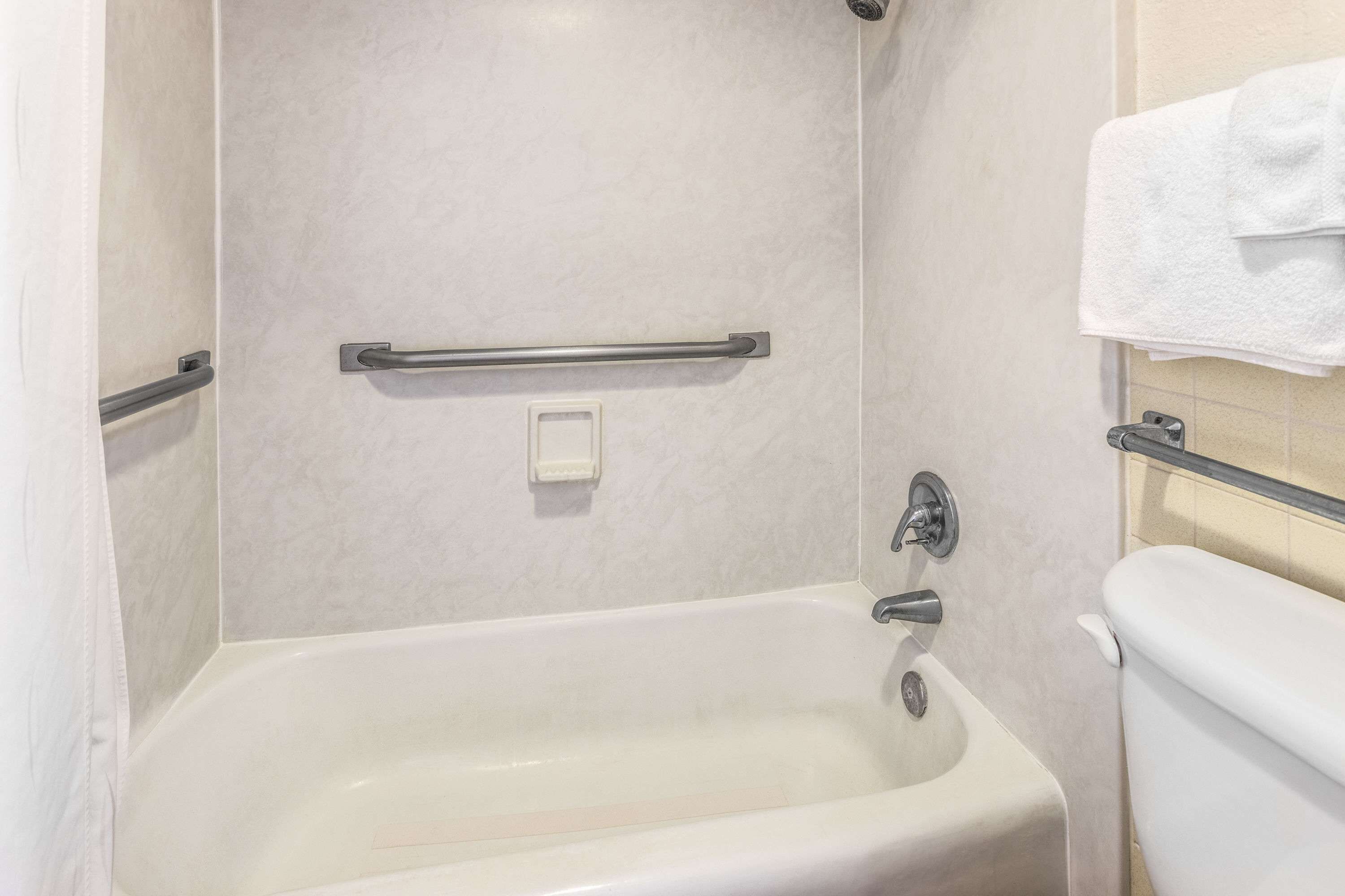 A bathroom with a bathtub, a toilet, and a shower area.