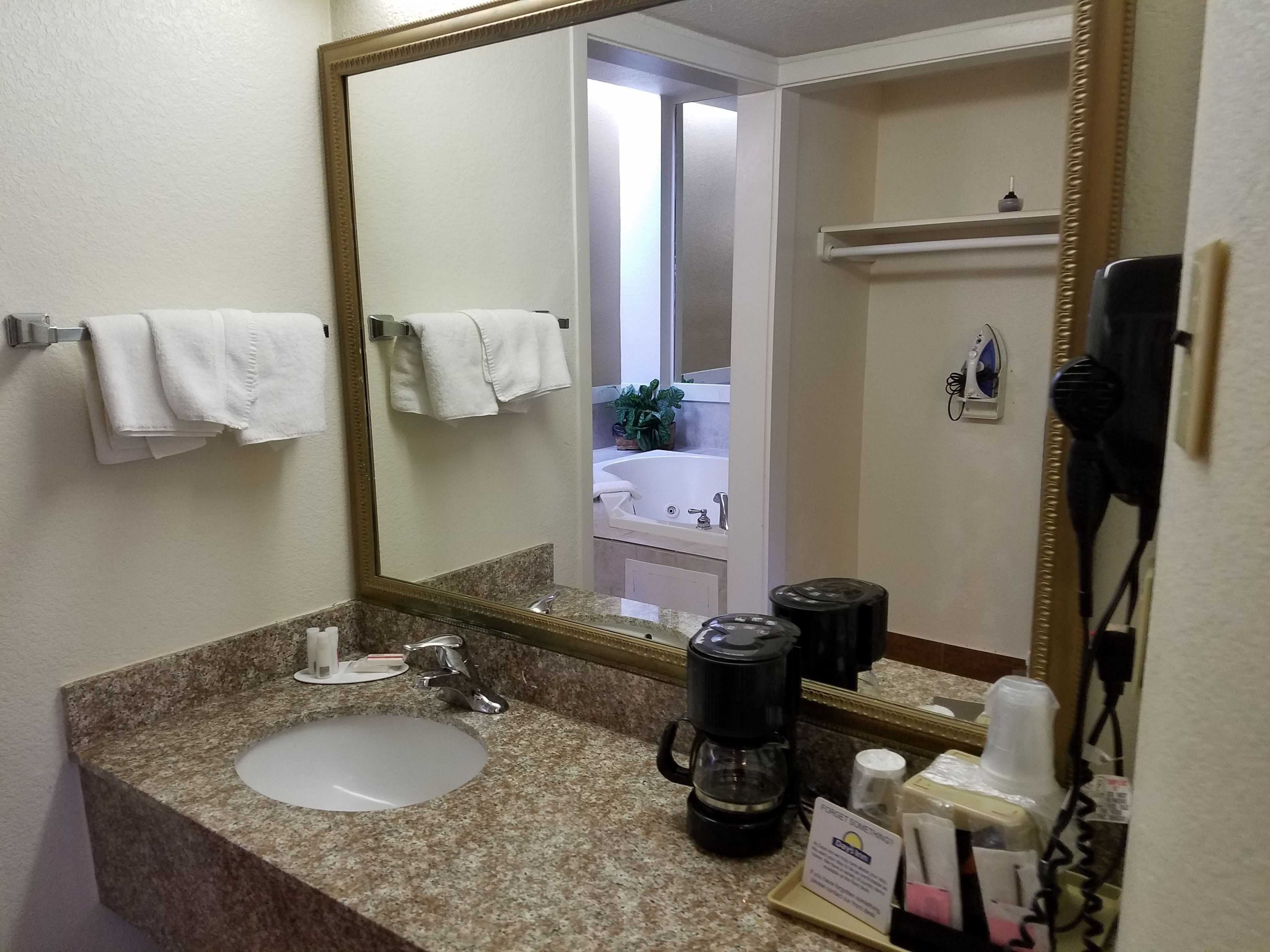 Une salle de bain d’hôtel équipée d’un lavabo, d’un miroir, d’un porte-serviettes et d’une machine à café.