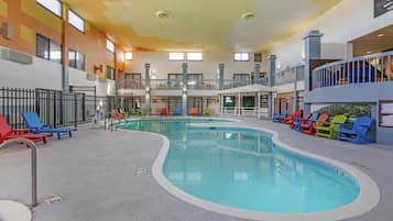 Una piscina cubierta con varias pistas de natación, rodeada de sillones de descanso y una zona de estar techada.
