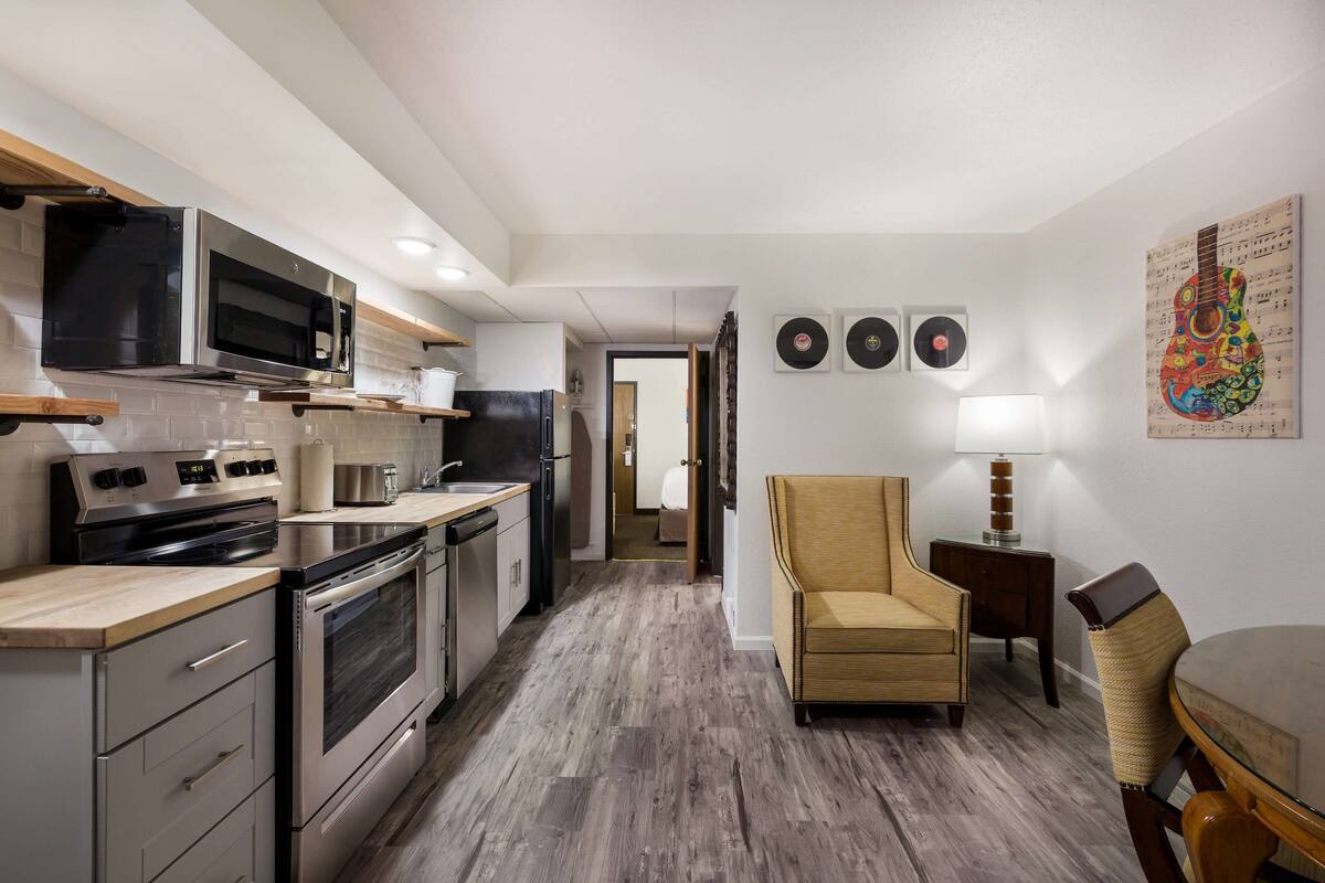 A modern kitchen with stainless steel appliances, a wooden countertop, and a dining area with a chair and table.