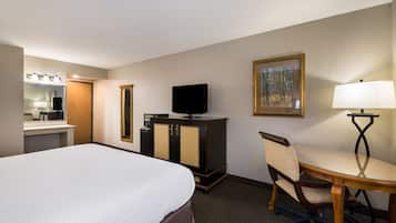 A hotel room with a large bed, a desk with a chair, a television on a cabinet, a painting on the wall, and a lamp.
