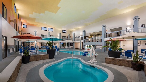 Una piscina interior con varios niveles, rodeada de sillones de descanso y sombrillas.