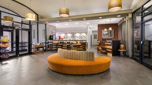 Un vestíbulo moderno con una zona de estar central, un bar y una recepción.
